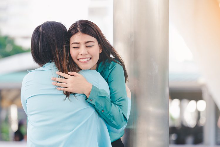 Portrait of happy asian women hugging each friend outdoor city background