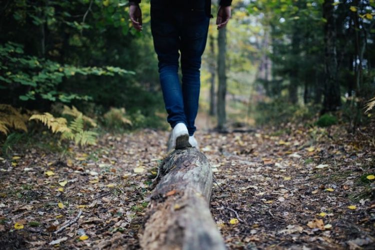 A man balances on a log in the woods