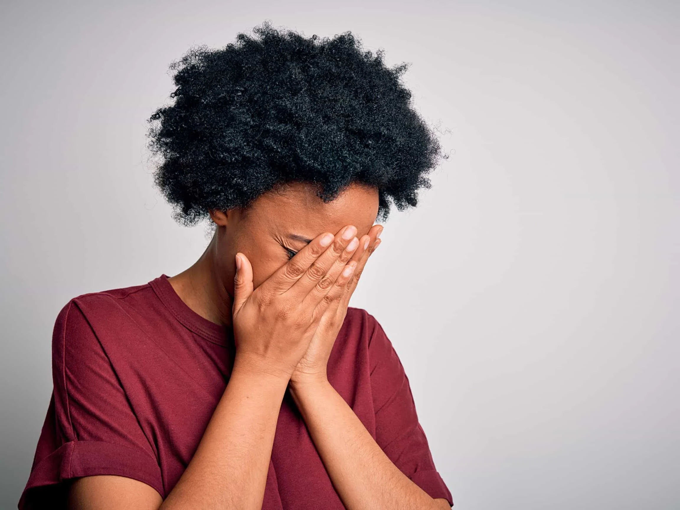 A woman experiencing trauma puts her head in her hands and cries