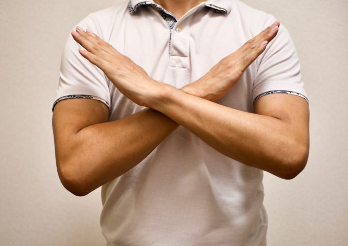 man in white T-shirt made X sign shape mean to say no