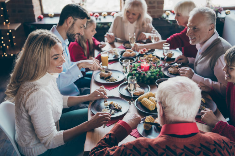 Photo of full family gathering sitting around dinner table communicating x-mas party tradition all together son daughter grandma grandpa in noel decorated living room indoors