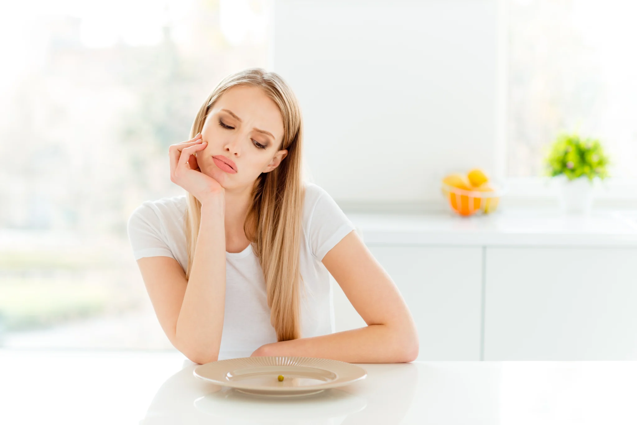 Portrait of irritated beautifiul teenager disappointed teen frustrated have lunch sit table touch chin tired unhealthy dressed trendy outfit in kitchen.