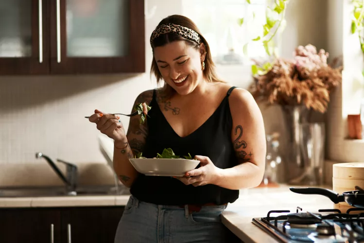 Shot of a young woman eating a healthy salad at home