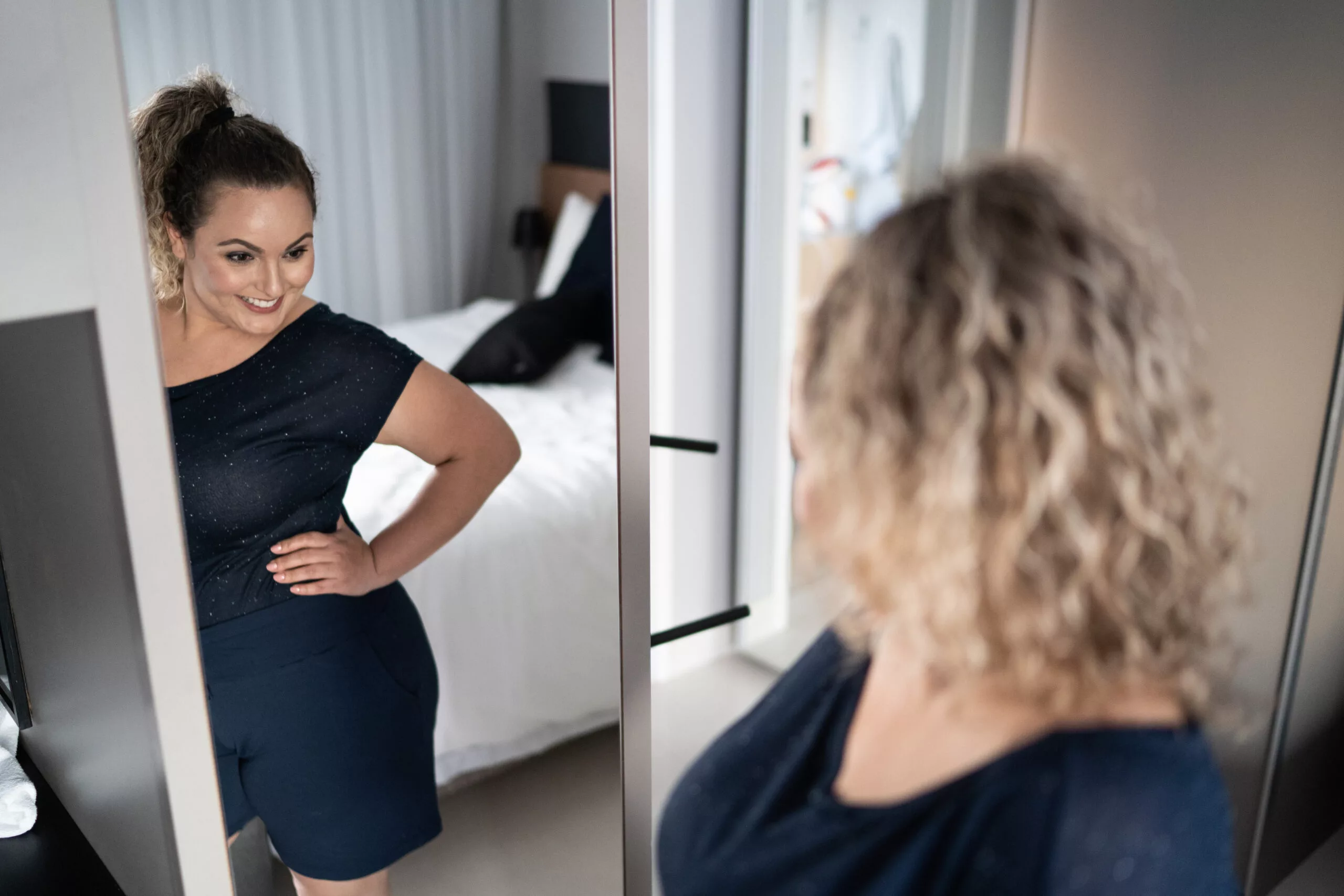 Pretty woman getting dressed in front of a mirror at home