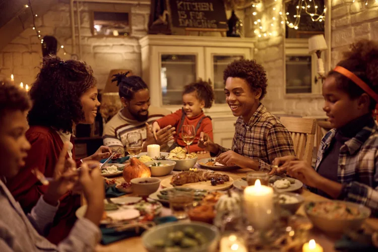 Happy African American family eating Thanksgiving dinner at dining table. Focus is on boy.