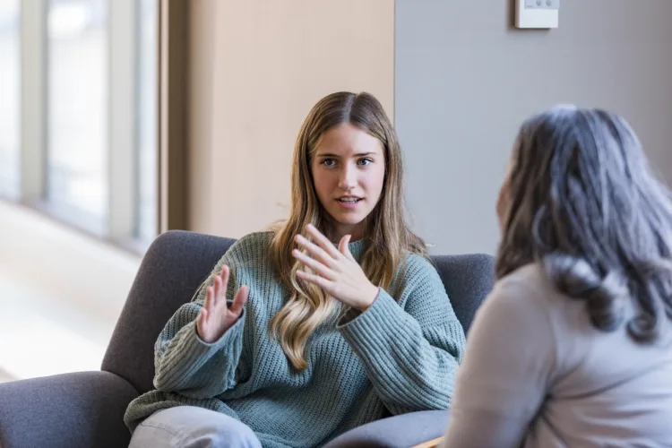 The young adult university student talks with her mature peer about her previous experiences.