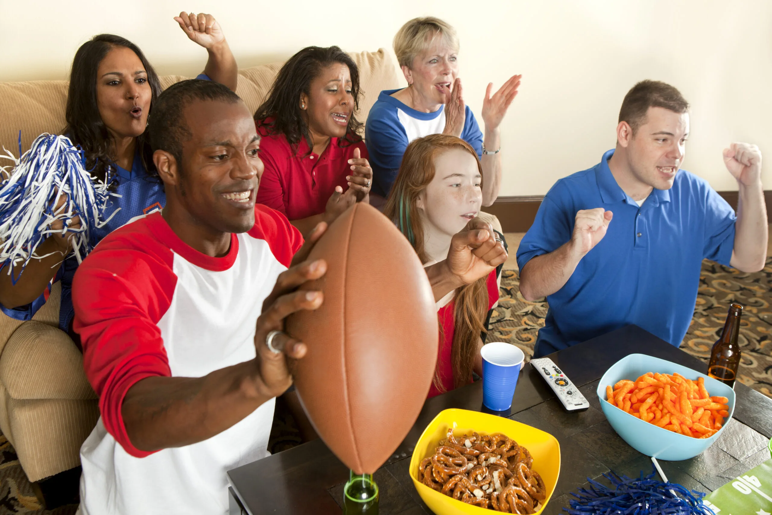 Diverse group of family and friends watching and cheering for a team.