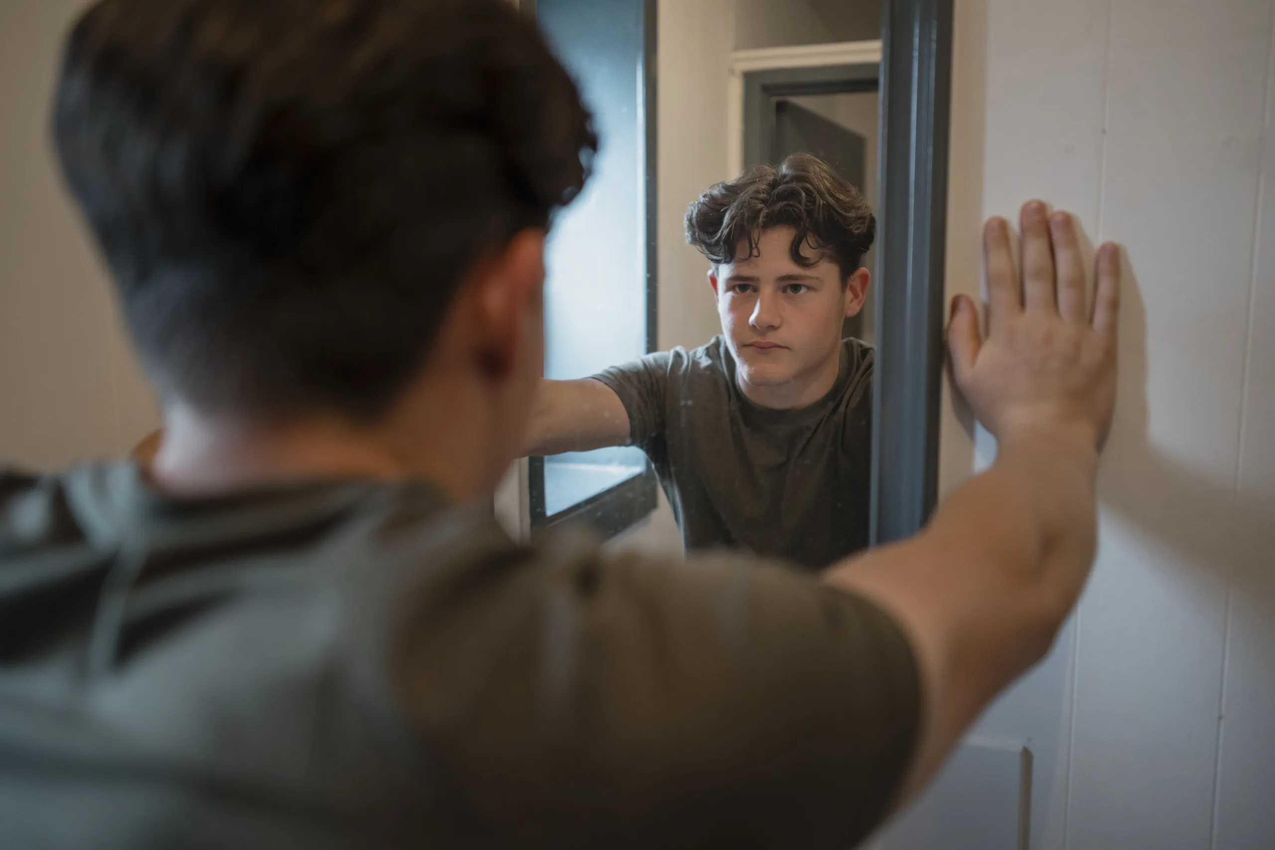 an-over-the-shoulder-shot-of-a-young-teenage-male-athlete-in-the-gym-changing-rooms-he-is-taking-a-break-from-his-gym-session-to-catch-his-breath-he-has-his-hands-on-the-wall-and-is-looking-at-his-ref-stockpack-gettyimages An over-the-shoulder shot of a young teenage male athlete in the gym changing rooms, he is taking a break from his gym session to catch his breath, he has his hands on the wall and is looking at his reflection in the mirror.