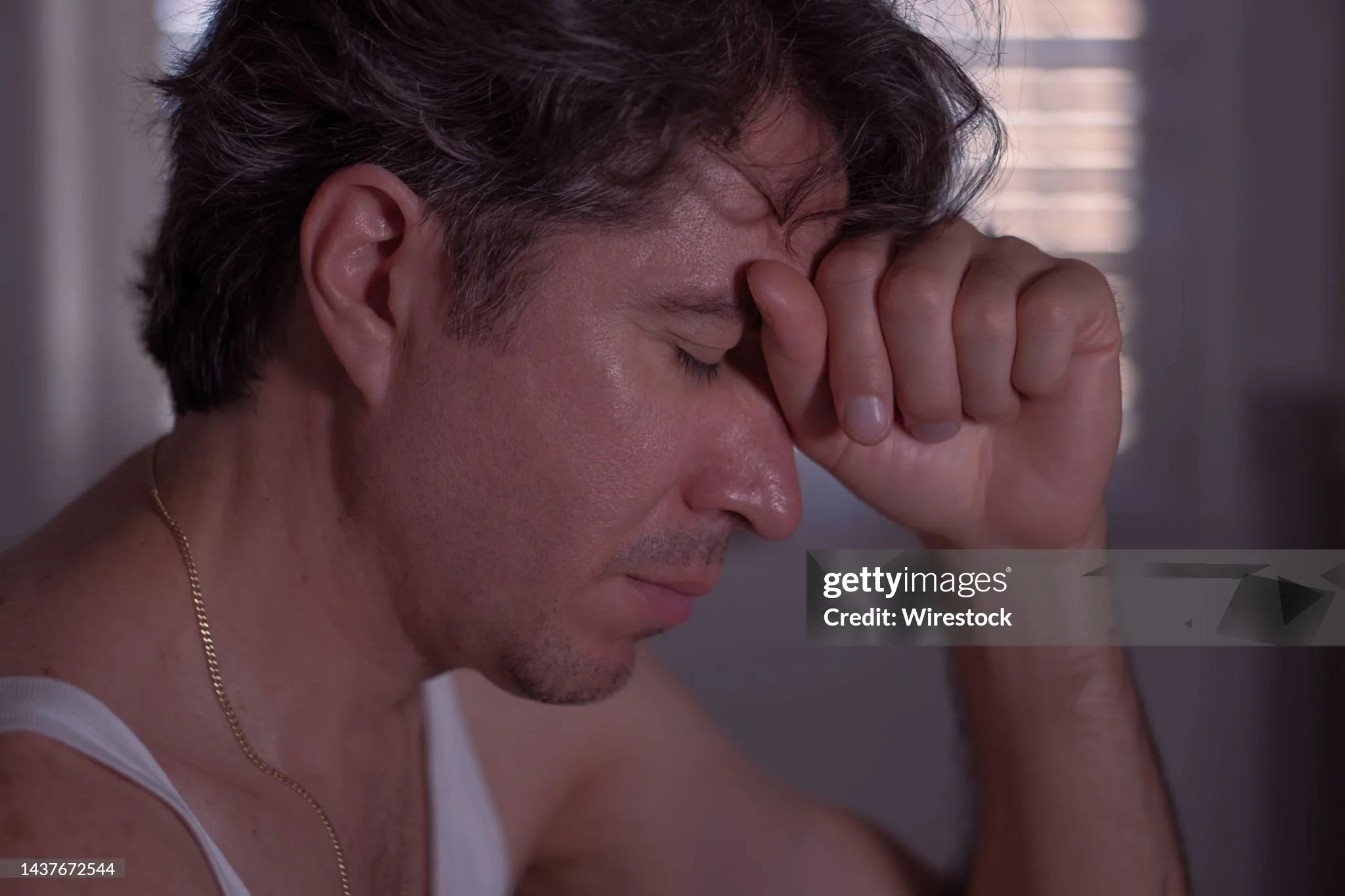 A grieving and worried man in the darkness of his room. Unhappy and stress concept.