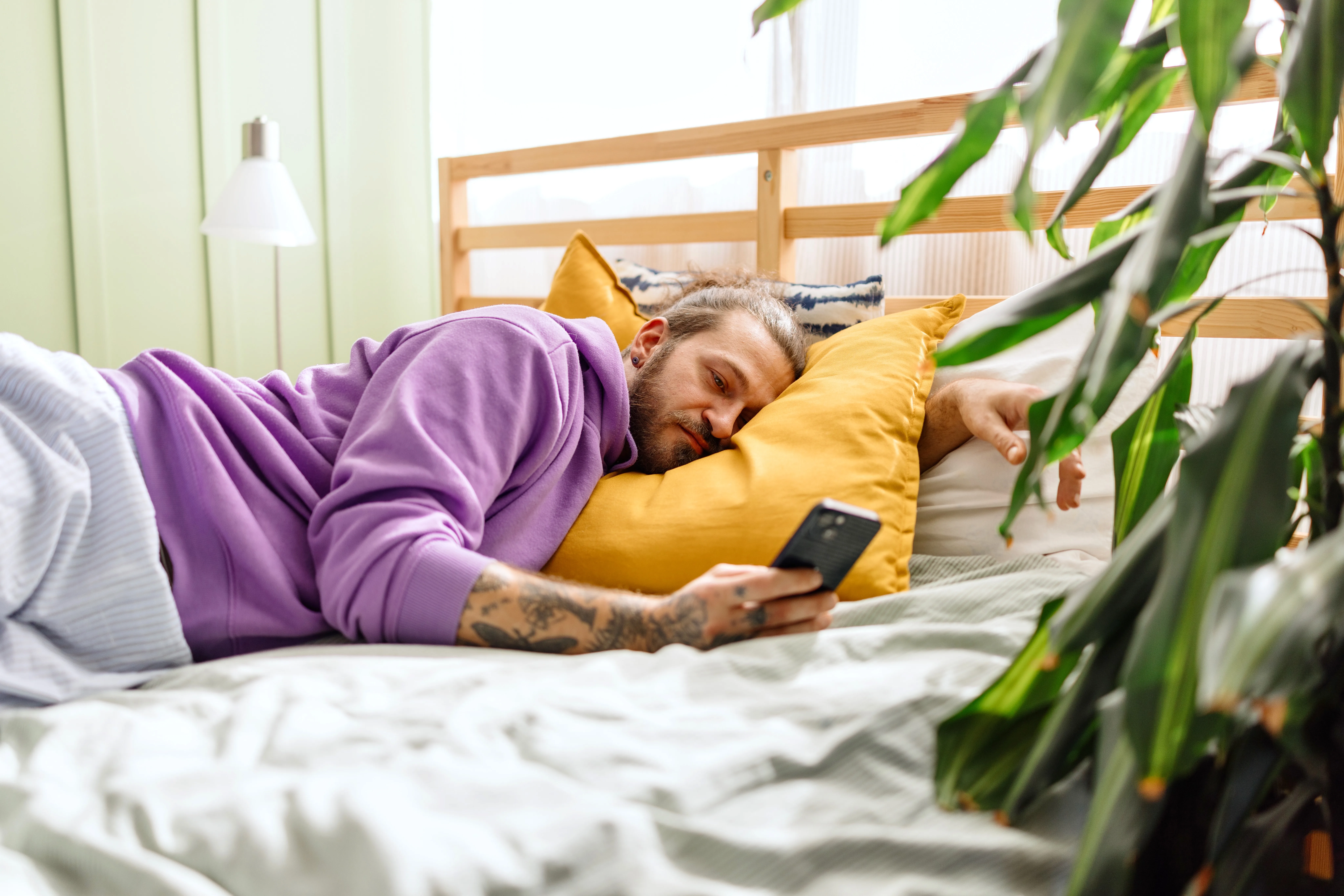 Man surfing the net while lying in bed during the day