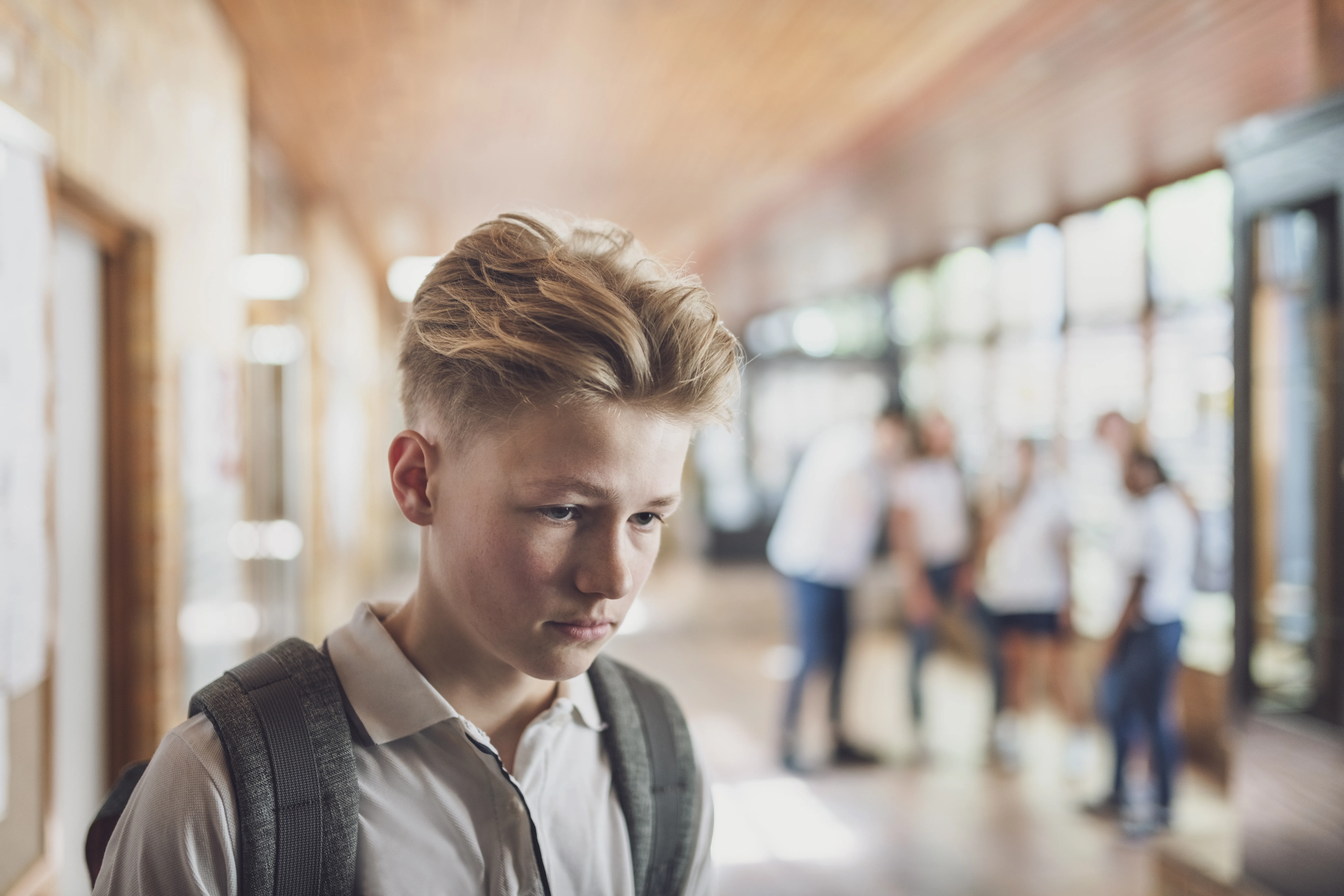 Teenage student being bullied by classmates in school about how he looks