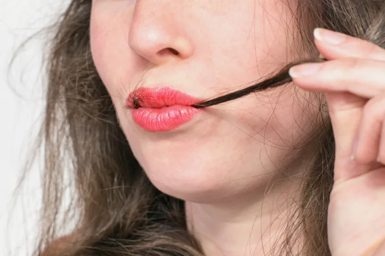 Young beautiful woman with hair strand in red lips. Trichophagia - compulsive eating of hair associated with trichotillomania (hair pulling)